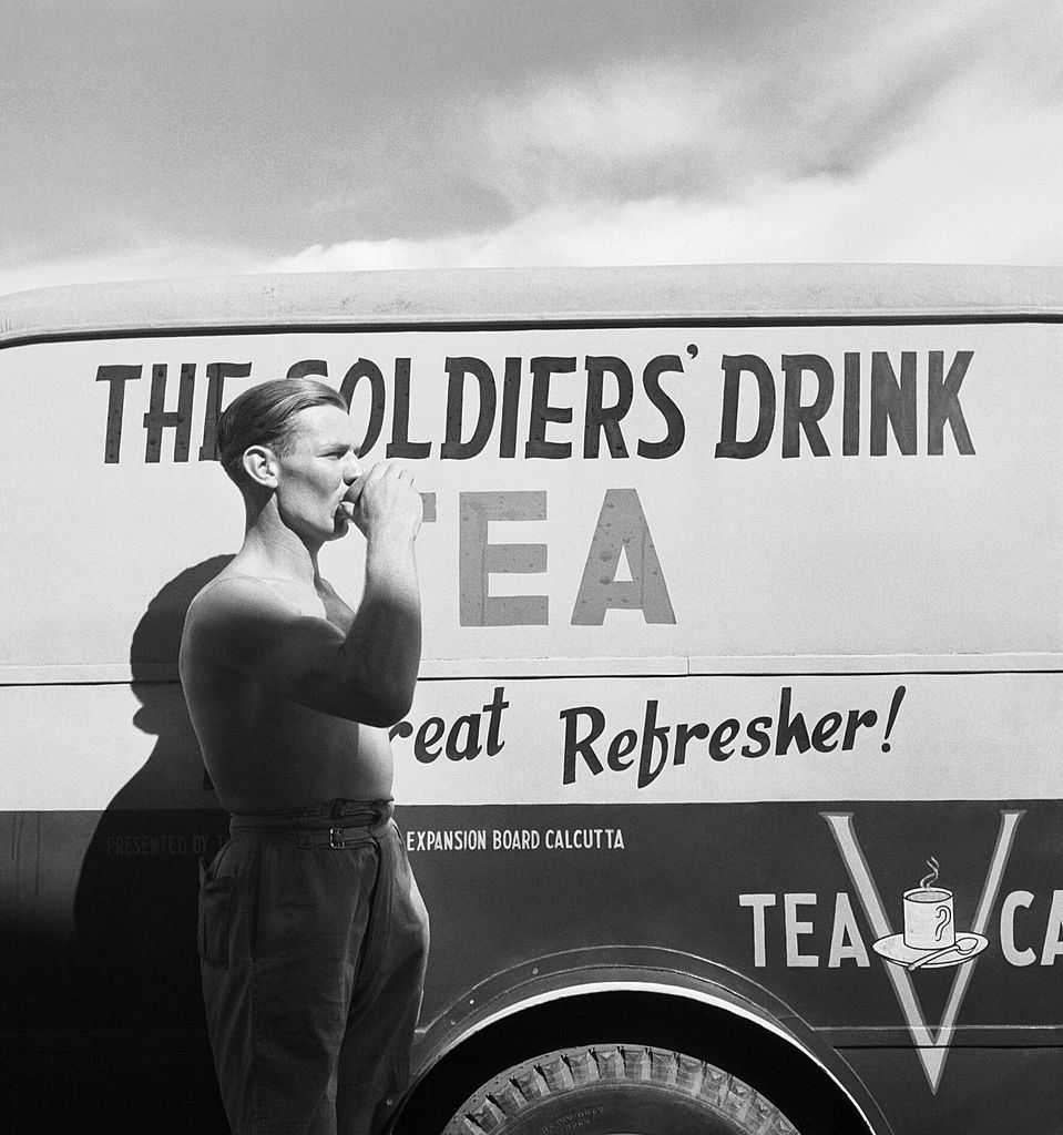 Cecil Beaton Photographs - General, India 1944: A soldier drinking a cup of tea next to a Red Cross Mobile tea wagon at Calcutta airport.